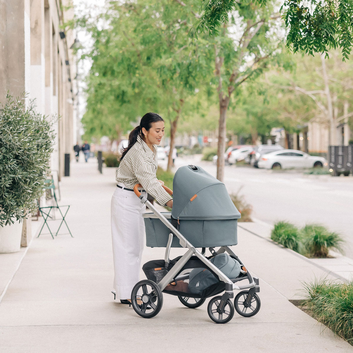 Woman checks on baby in bassinet attached to UPPAbaby VISTA V3 Stroller - CALLUM (Stone Blue)