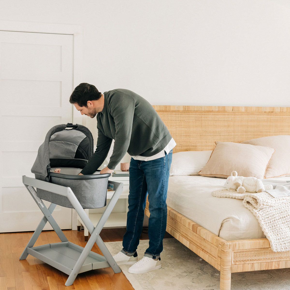 Dad checks on baby inside of bassinet attached to UPPAbaby New Bassinet Stand - Grey