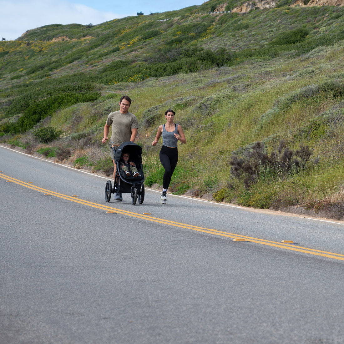 Mom and dad jog down road pushing Bumbleride 2024 Speed Jogging Stroller - Black