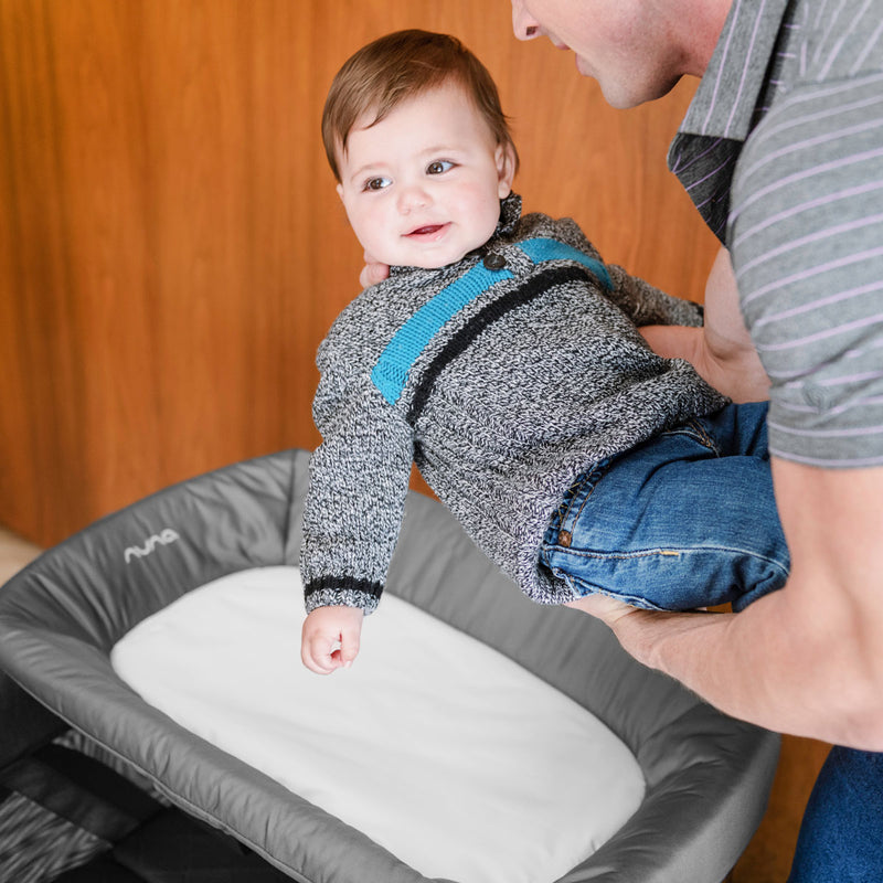 Dad places toddler on Nuna SENA Changer 