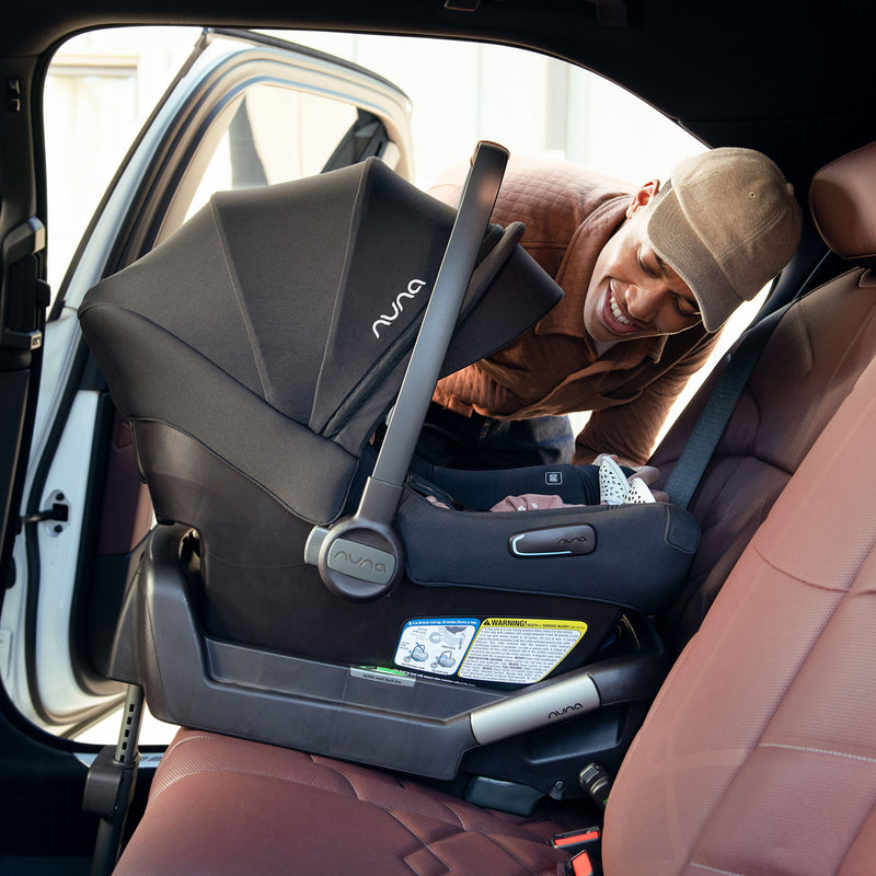 Dad smiles at baby riding in vehicle in Nuna PIPA Aire Infant Car Seat with Base - Caviar