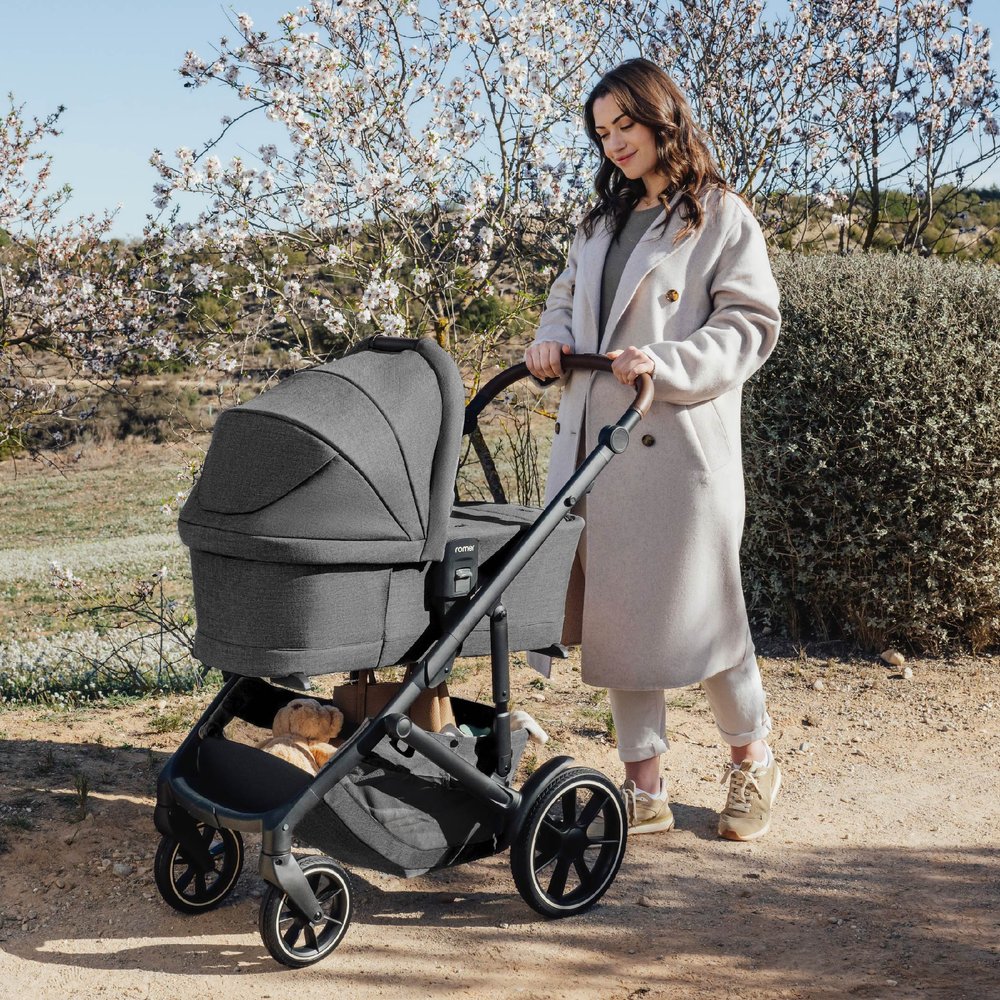 Mom pushes baby in bassinet attached to Romer Tura Stroller - Peppercorn