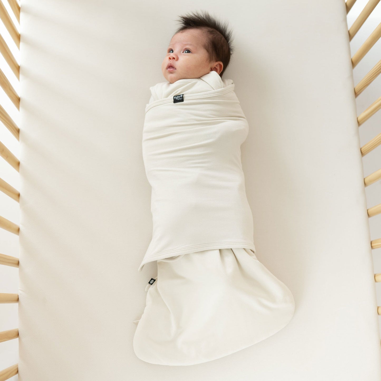 Newborn baby wrapped in Kyte BABY Sleep Bag Swaddler - Ecru - XS