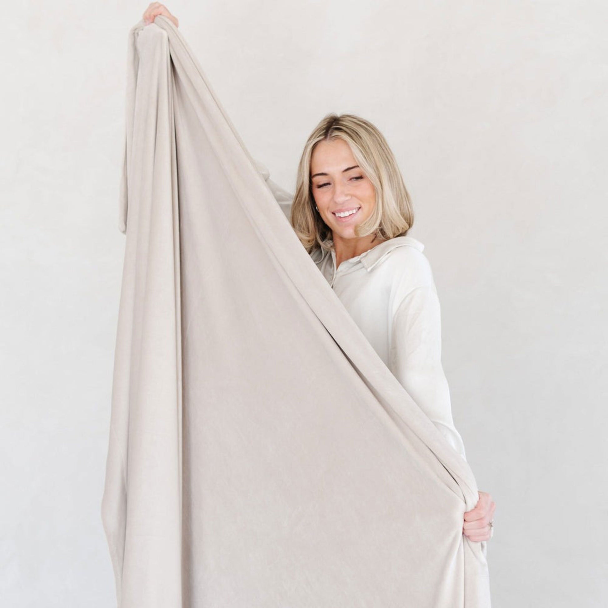 Woman holds Saranoni Minky Stretch XL Throw Blanket - Buttermilk