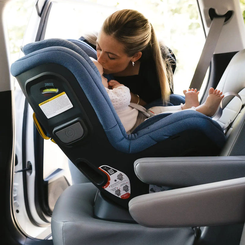 Mom kisses baby sitting rear-facing in UPPAbaby Rove Convertible Car Seat - Cody - Coastal Blue Mélange