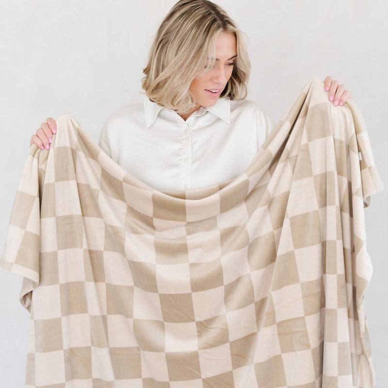 Woman holds up Saranoni Minky Stretch XL Throw Blanket - Neutral Checkered